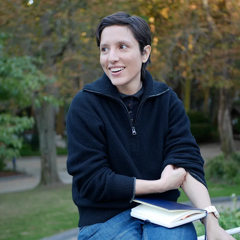 Mujer emprendedora usando su portátil en casa, rodeada de un ambiente de cocina y trabajo.